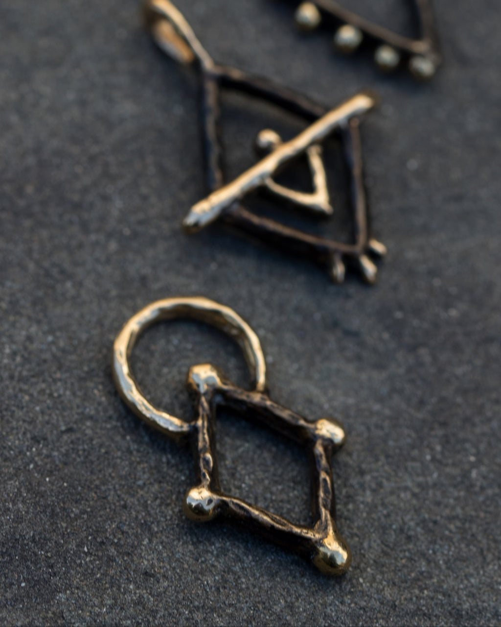 Geometric gold pendants on a dark surface