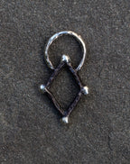 Silver geometric pendant on a dark textured surface